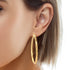 A close-up showcases a person's ear adorned with the Huge Zigzag Texturized Hoops Earrings Round gold filled, their bold design standing out elegantly against the person's short, light brown hair.
